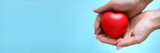 Fototapeta  - Woman hand hold red toy heart in hand against blue background closeup. Charity people concept
