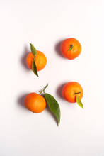 Overhead View Of Fresh Satsumas With Leaves Against White Background