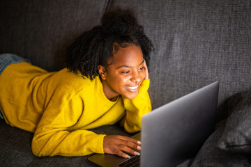 Wall Mural - smiling young african american woman looking laptop computer screen