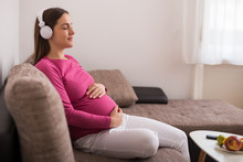 Beautiful Pregnant Woman Enjoys Listening  Music At Her Home.