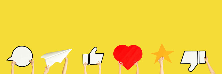 Hands holding the signs of social media on yellow studio background, flyer. Copyspace for your text or image, advertising. Showing meaning, gadgets, modern technologies, comments, message