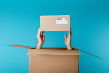 Cropped View Of Courier Holding Cardboard Box From Package Isolated On Blue