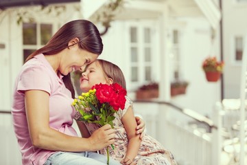 Canvas Print - Happy beautiful mother and daughter hugging with a bouquet