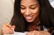 Smiling black woman write story in notebook preparing for college