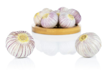 Wall Mural - Lot of whole fresh purple single clove garlic on bamboo coaster isolated on white background