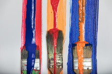 Thick Colorful Textured Paint Dripping Onto Paint Brushes Smeared Red Orange And Blue Paint