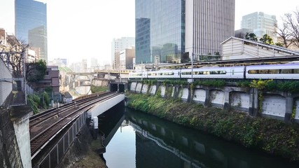 Canvas Print - Japan tokyo's train running out from the underground tunnel in early morning cross small river in winter day among high-rise building