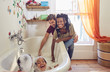 © Trevor Adeline/Caia Image - Parents giving playful daughters bubble bath