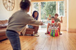 © Trevor Adeline/Caia Image - Young family playing bowling in living room