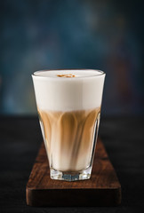 Glass of coffee flat white on a wooden board.