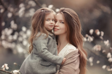 portrait of a mother with a baby against the background of blossoming white trees.
