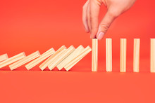 Hand Finger Stops Falling Wooden Dominoes, Red Background, Domino Principle, Business Concept