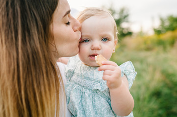 portrait of a daughter toddler hugging mother on nature on summer day vacation. mom and girl playing