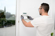 © W PRODUCTION - handsome man worker installing alarm technology insurance in home for burglar prevention