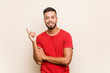 © Asier - Young south-asian man smiling cheerfully pointing with forefinger away.