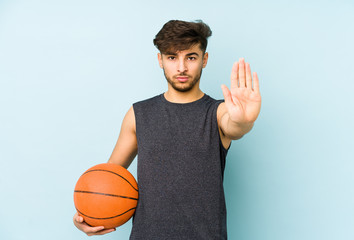 Young arabian man playing basket isolated standing with outstretched hand showing stop sign, preventing you.