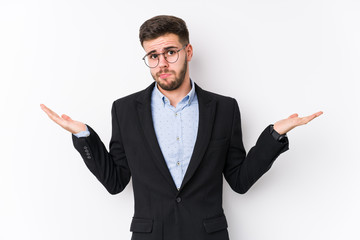 Young caucasian business man posing in a white background isolated Young caucasian business man doubting and shrugging shoulders in questioning gesture.