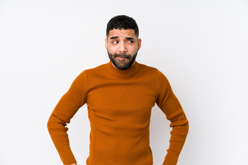 Wall Mural - Young latin man against a white background isolated confused, feels doubtful and unsure.