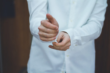 Young successful guy straightens his sleeve on a white shirt