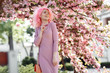 © Screaghin - Happy young woman with curly pink hair and sunglasses near the blossoming spring tree.