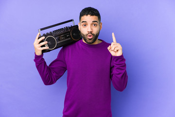 Wall Mural - Young arabian man holding a radio cassette isolated Young arabian man listening music having some great idea, concept of creativity.