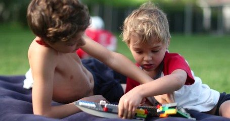 Wall Mural - Kids playing with toys outside in home backyard. Authentic real life playful children siblings