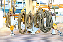 Hempen Lines Neatly Coiled On A Beautiful Vintage Classic Sailing Ship. Beautiful Teak Planks Of The Deck And Big Wooden Blocks And Shackles At The Base Of The Main Mast.