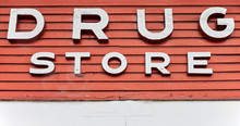 Close-up Of A Drug Store Sign Over The Entrance Of A Pharmacy In Asia. White Painted Letters Are Fixed On Red Peeling Off Painted Wooden Panels