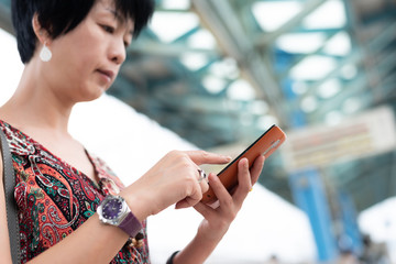 Poster - mature traveling woman waiting and using a cellphone