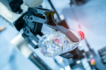 robot hand holding a bottle of wate on blurred background, artificial intelligence concept. Automatic industrial machinery equipment.