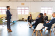 © Mangostar - Side view of confident speaker standing near whiteboard. Group of employees discussing ideas during presentation of new project at briefing. Business meeting concept