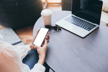 Mockup image blank white screen cell phone.woman hand holding texting using mobile on desk at coffee shop.background empty space for advertise text.people contact marketing business,technology