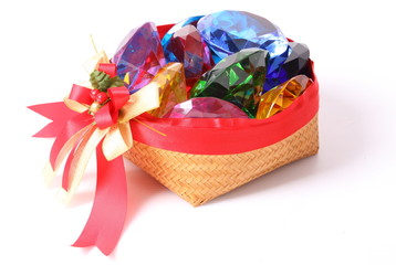 Colored assorted gemstones in bamboo basket isolated on a white background