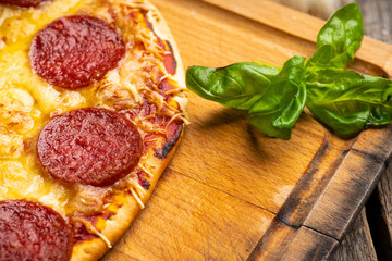 Wall Mural - Fresh pepperoni pizza served on the wooden board. Selective focus. Shallow depth of field.