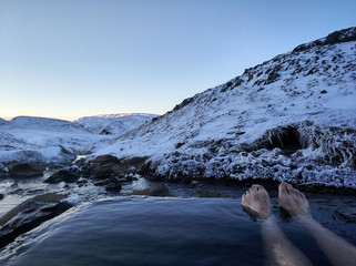 Wall Mural - The girl lies in a hot spring in the open air with a gorgeous scenery on the snowy mountains. Amazing Iceland in the winter