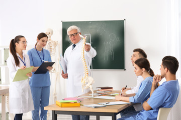 Canvas Print - Medical students and professor studying human spine structure in classroom