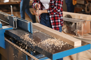 Wall Mural - Female carpenter cleaning surface planer with air blow gun in workshop, closeup