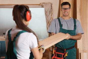 Canvas Print - Professional carpenters with wooden plank in workshop