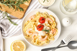 Fototapeta Tulipany - Delicious pasta with shrimps served on white wooden table, flat lay