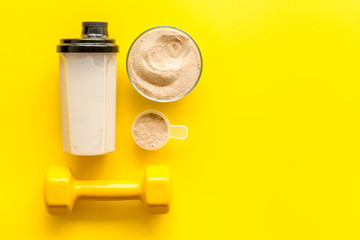 Wall Mural - Sport diet. Protein shake near dumbbells on yellow background top-down flat lay copy space