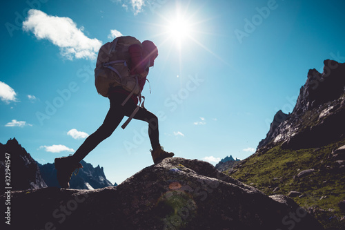Fotografía Successful woman hiker hiking in sunrise mountains