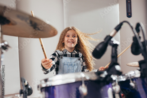 Fotografía young girl playing drums in music studio
