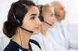 © rogerphoto - Call center operators at work. Focus at beautiful latin american woman in headset