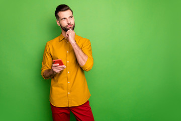 Portrait of his he nice attractive serious minded guy in formal shirt holding in hand cell thinking creating smm idea isolated on bright vivid shine vibrant green color background