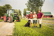 © MACO - Portrait of farming family laughing after long day of work with dag, tractor and barn. Laurel, Montana, USA
