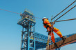 Safety man worker sprinkle, ropeaccess from structure steel with safety harness and wearing equipment protective PPE on blue sky background
