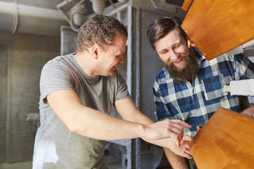 Lehrling und Ausbilder kontrollieren ein Holz Brett