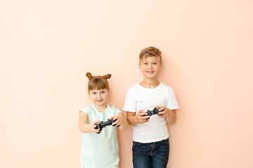 Canvas Print - Little children playing video games on color background