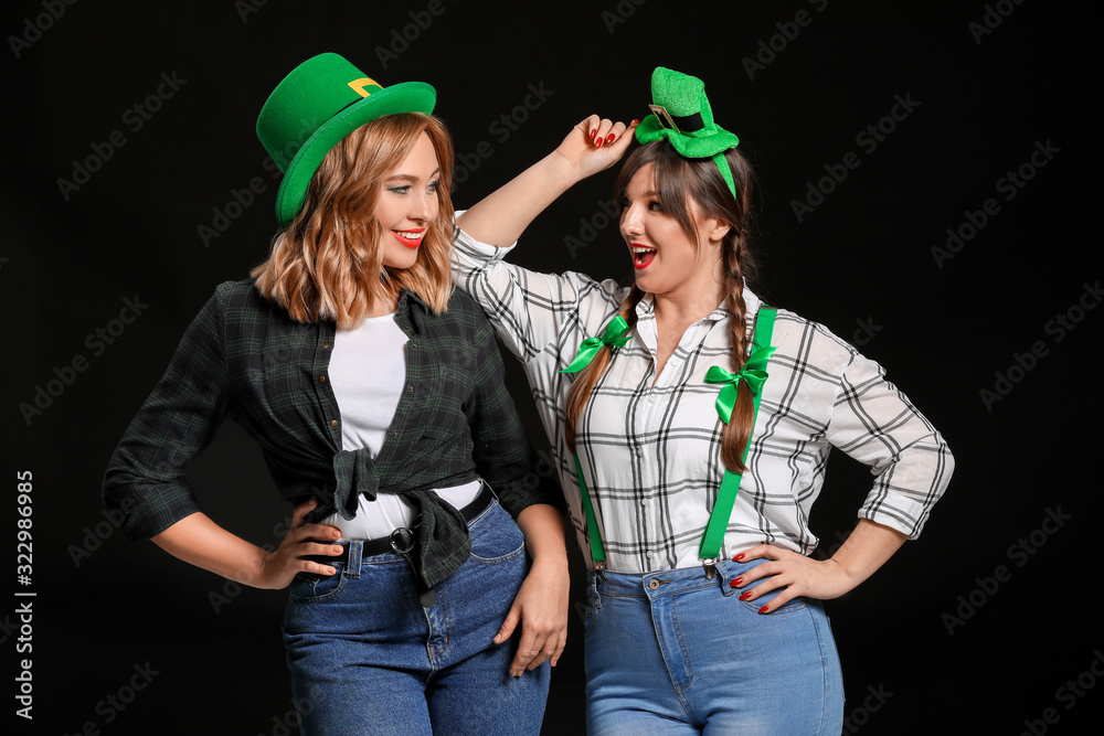 Funny young women on dark background. St. Patrick's Day celebration