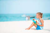 Fototapeta Morze - Adorable little girl playing with beach toys on white tropial beach